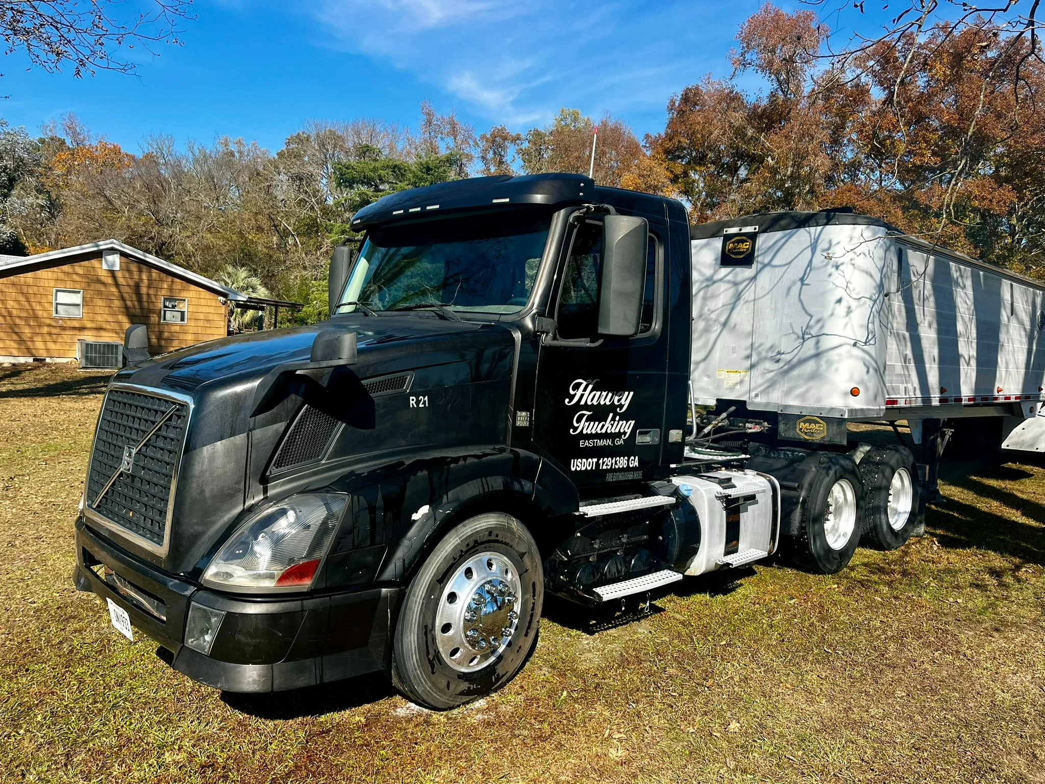 Same black tractor and trailer after washing, with cleaner wheels and body panels